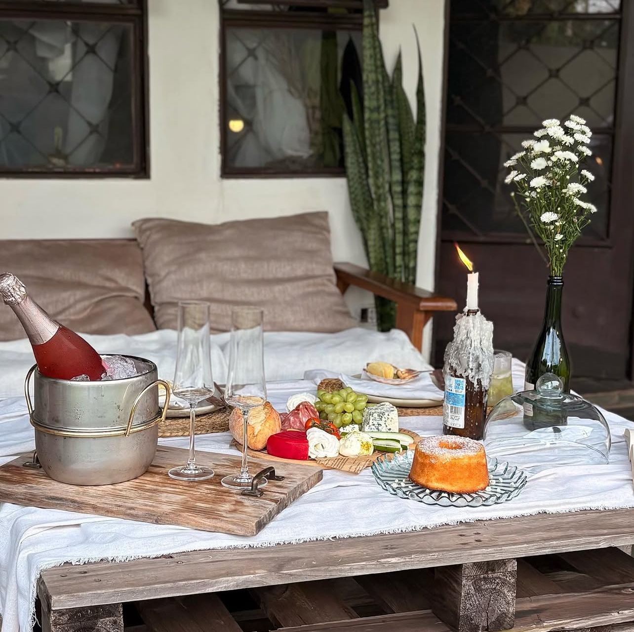 Mesa de tábua de frias com espumante e flores no espaço externo